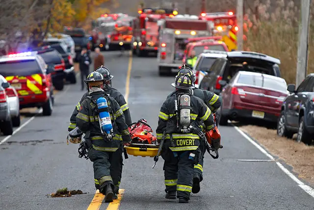 Firefighters carry a stretcher to the scene of a fatal fire at 15 Willow Brook Rd., in Colts Neck, N.J.